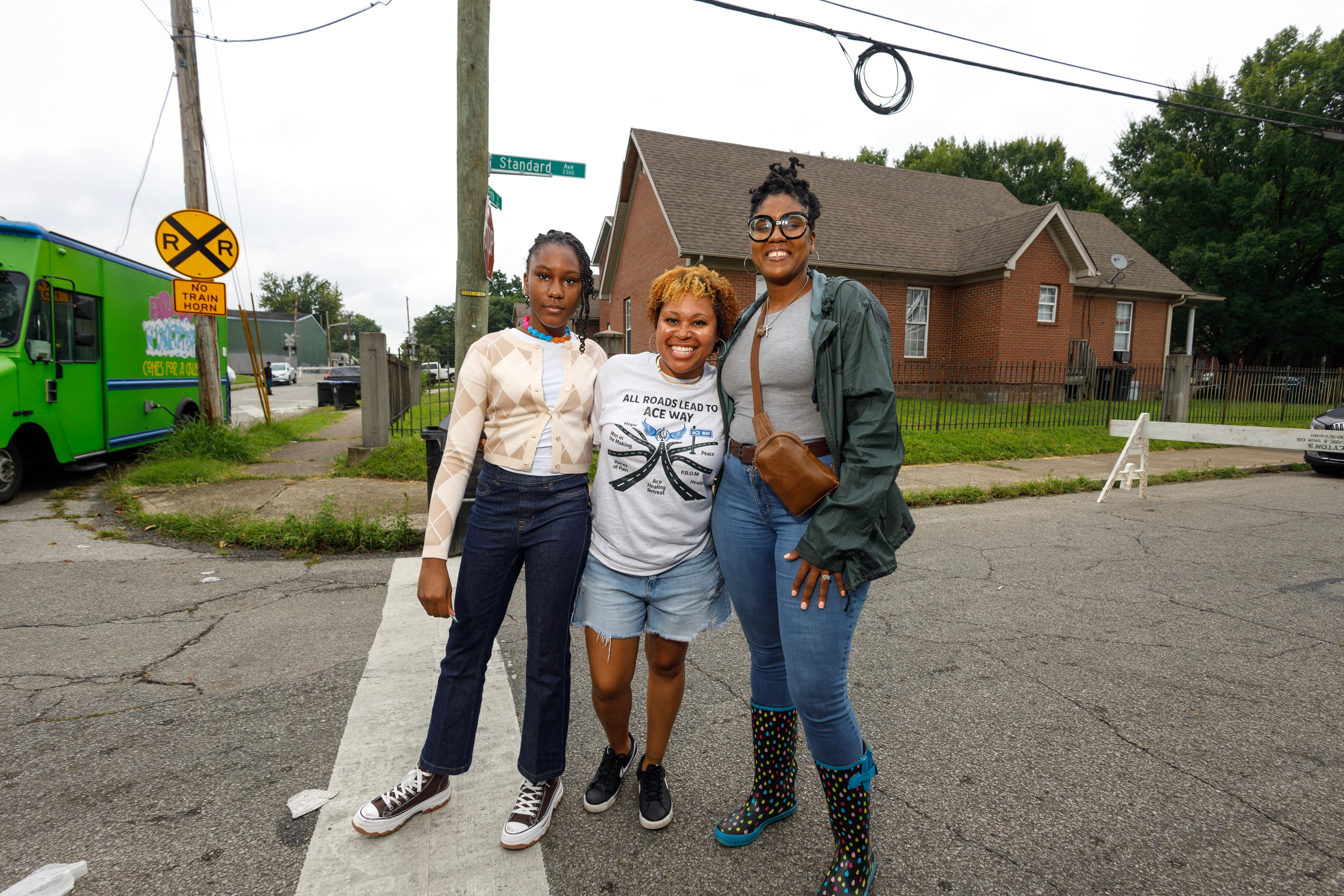 Three community members posing on the street at ACE Way block party
