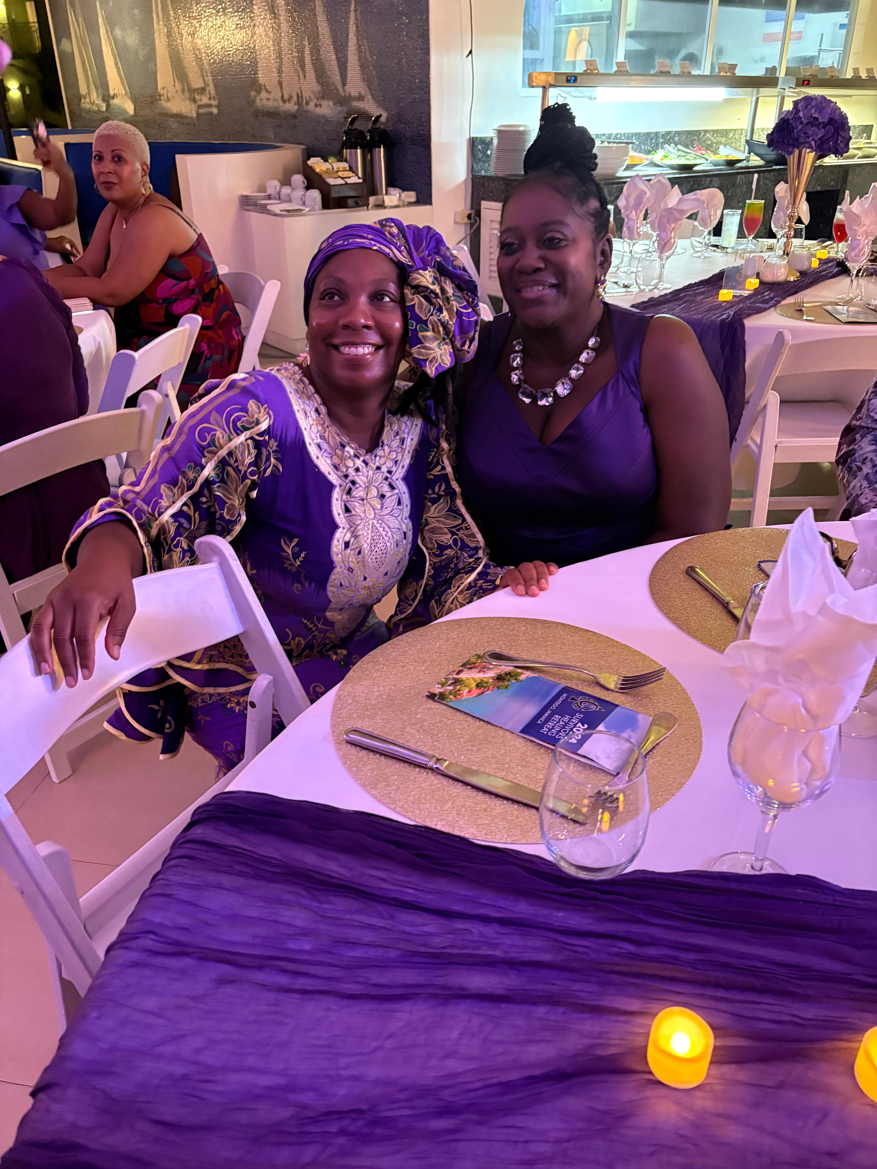 Two women in purple attire at the 2024 Survivors Healing Retreat dinner