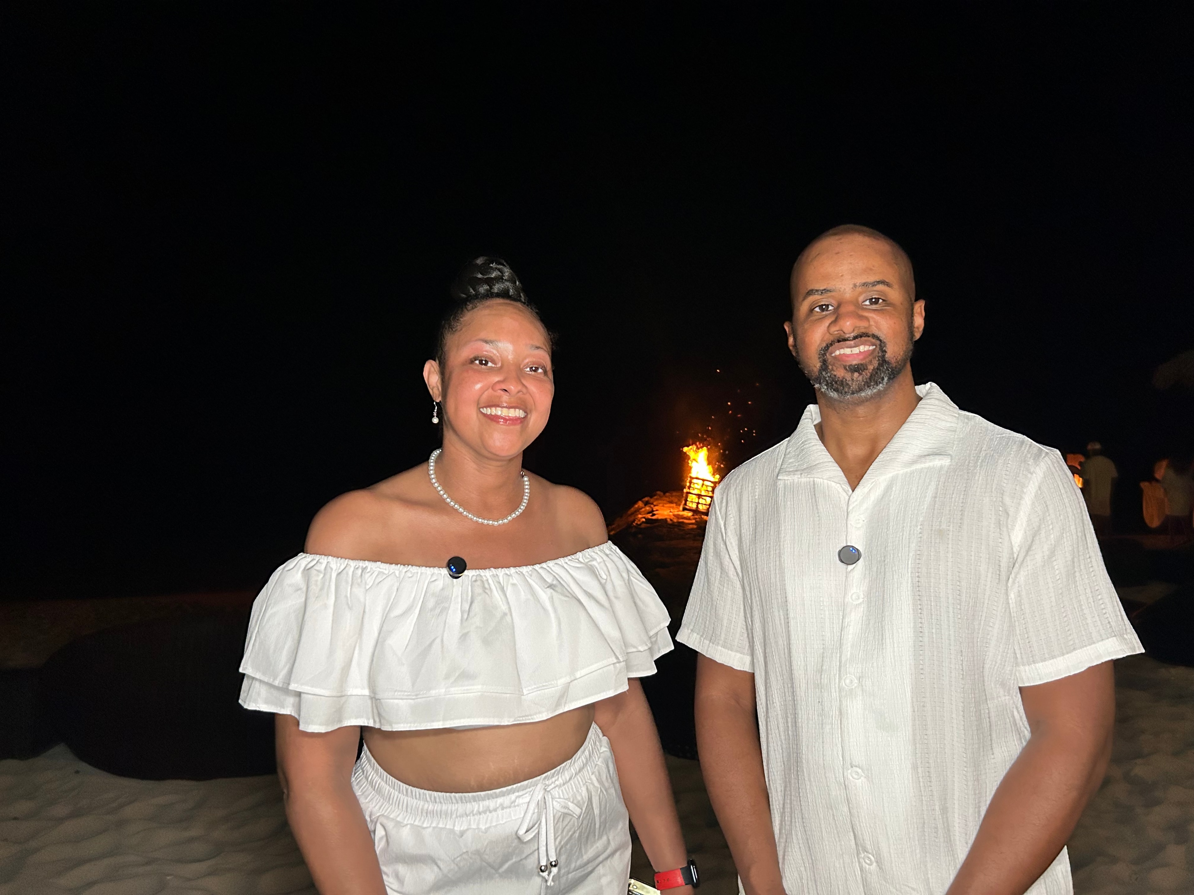 Two retreat participants in white outfits at beachside bonfire
