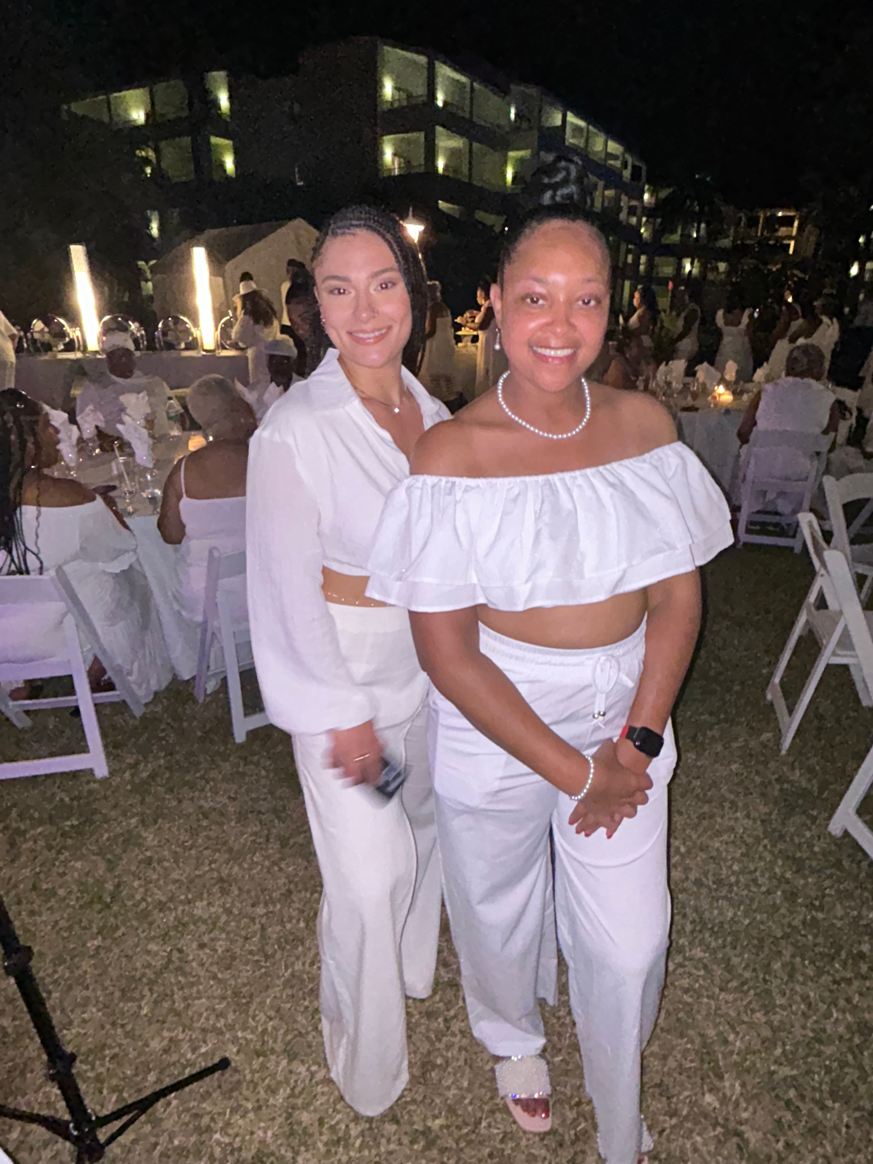 Two women in white embracing at the healing retreat outdoor ceremony