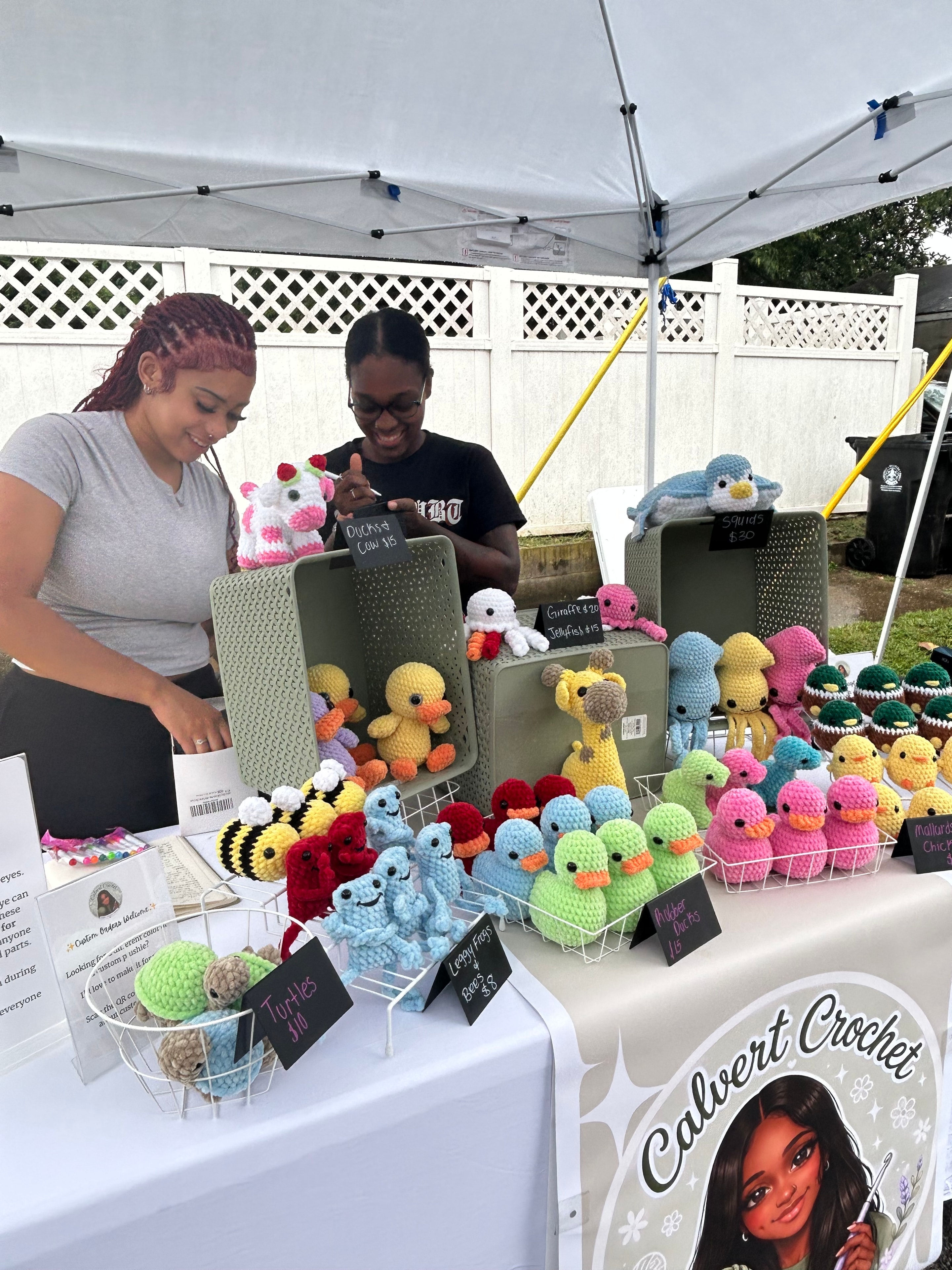 Vendor and customer at Callvent Crochet booth with colorful handmade animals at ACE Way block party