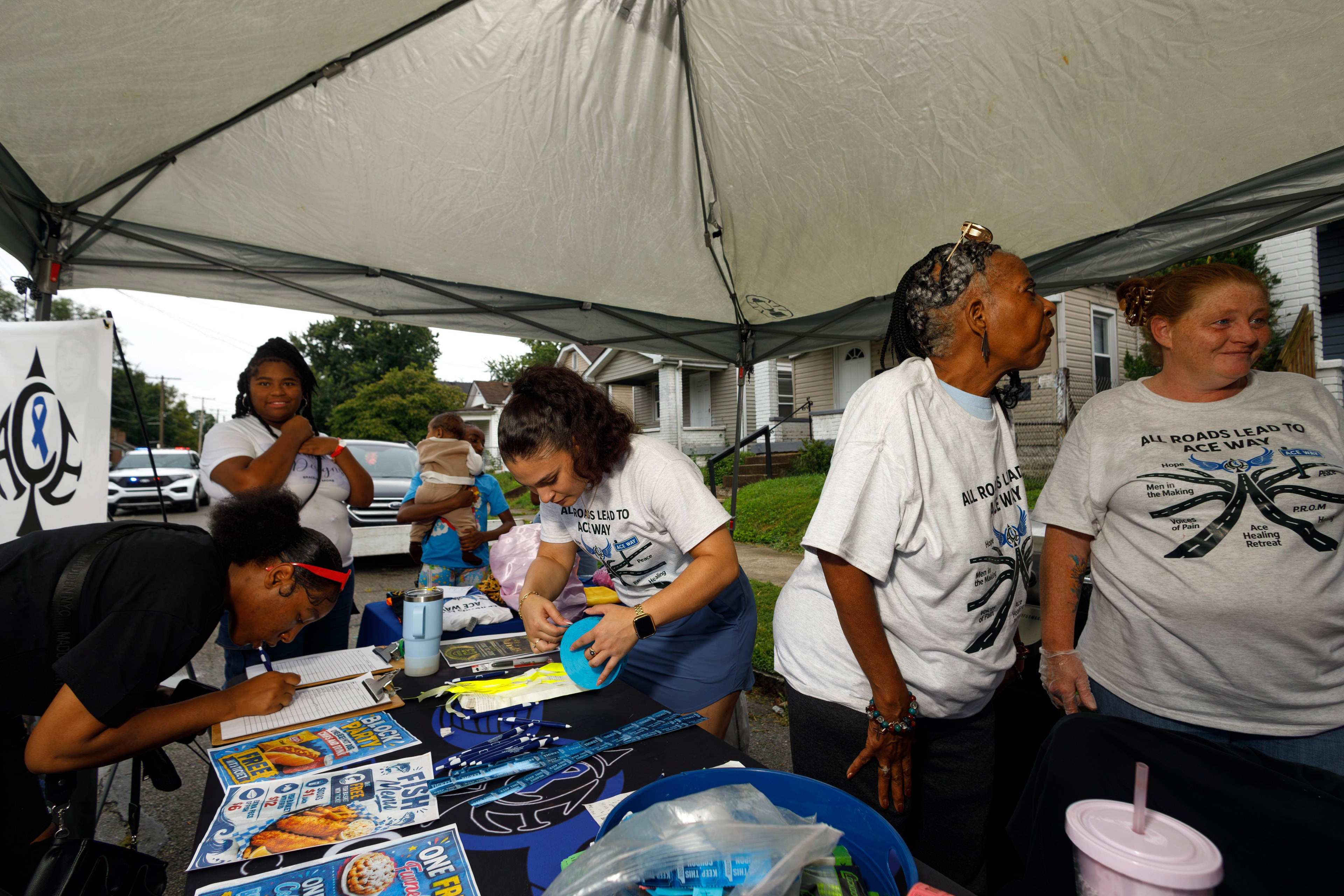 ACE Project volunteers staffing registration table under tent at block party