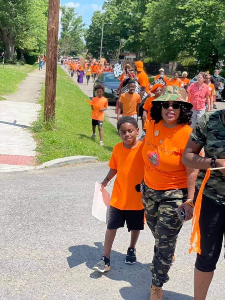 Rose Smith leading Wear Orange walk with youth in orange shirts marching down street