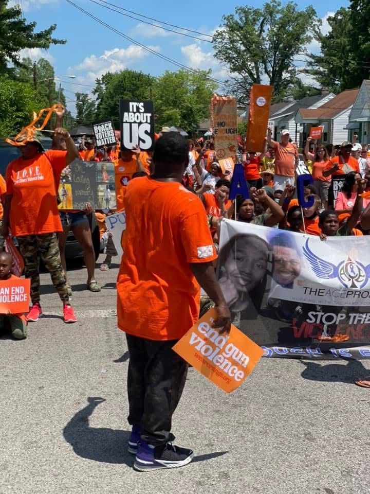 Large crowd in orange shirts at gun violence awareness march holding End Gun Violence signs