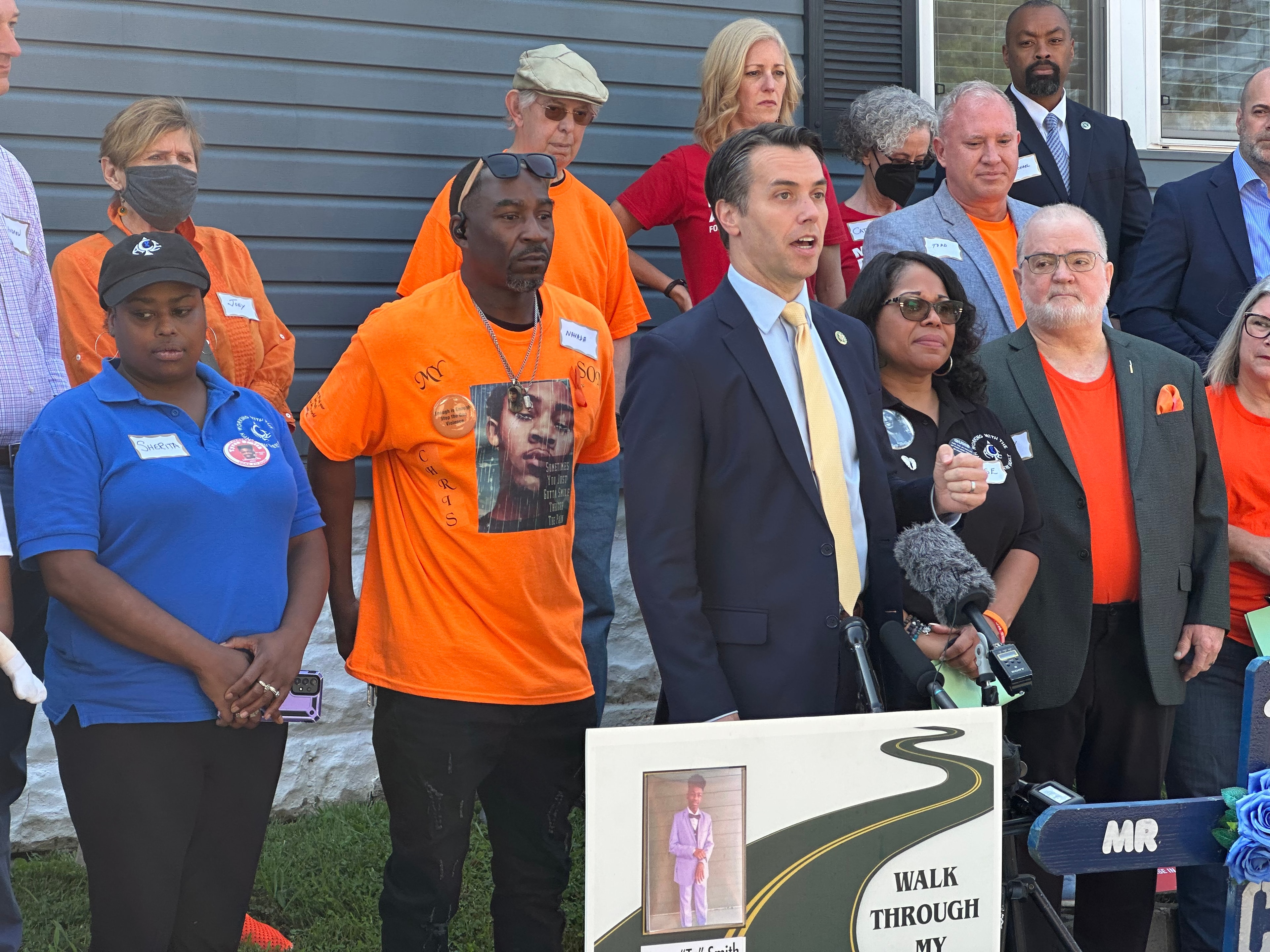 Speaker at podium with community members at Walk Through My Pain gun violence event