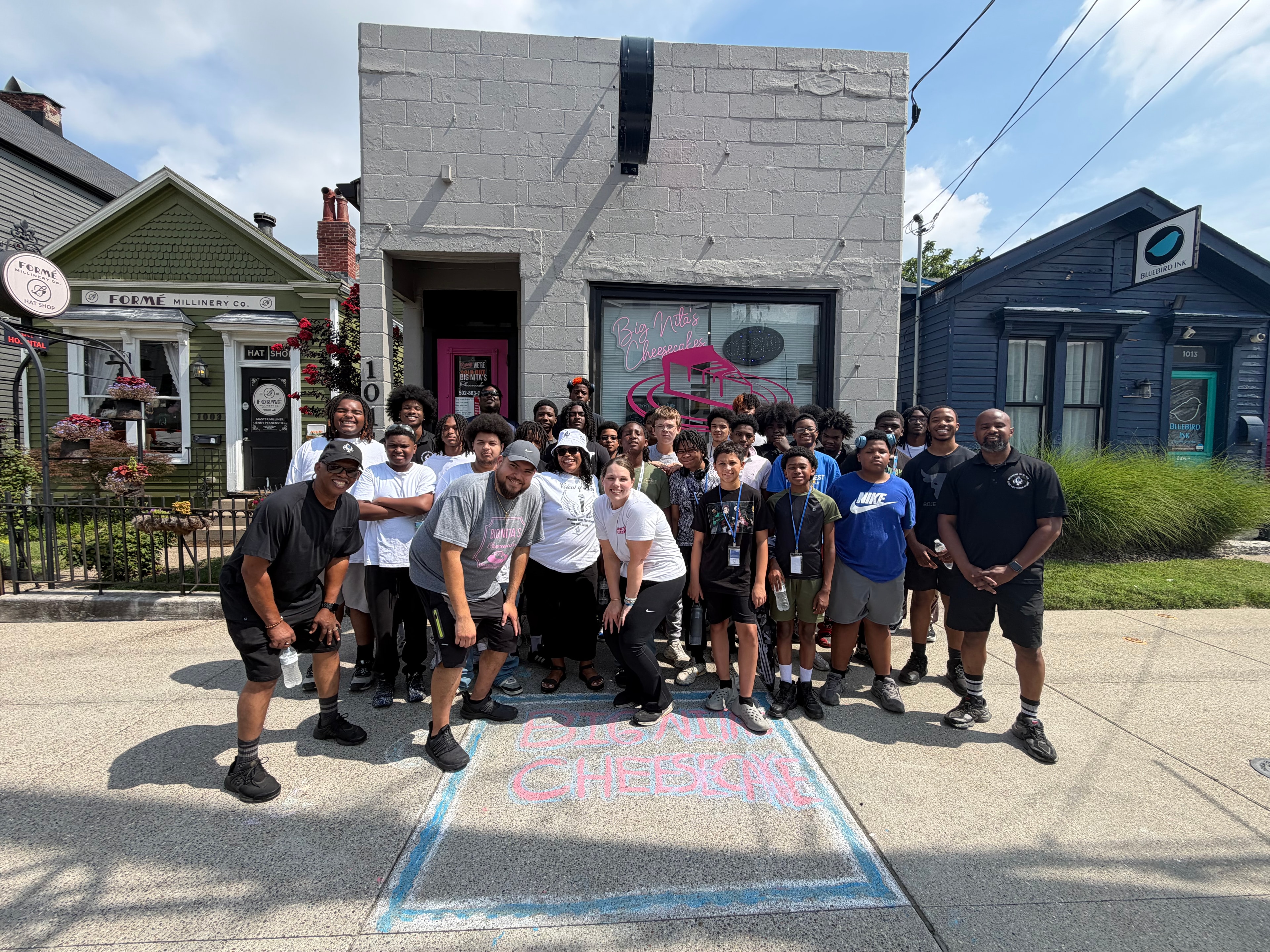 Large group of youth and mentors posing outside Big Nita's Cheesecakes on Men in the Making field trip
