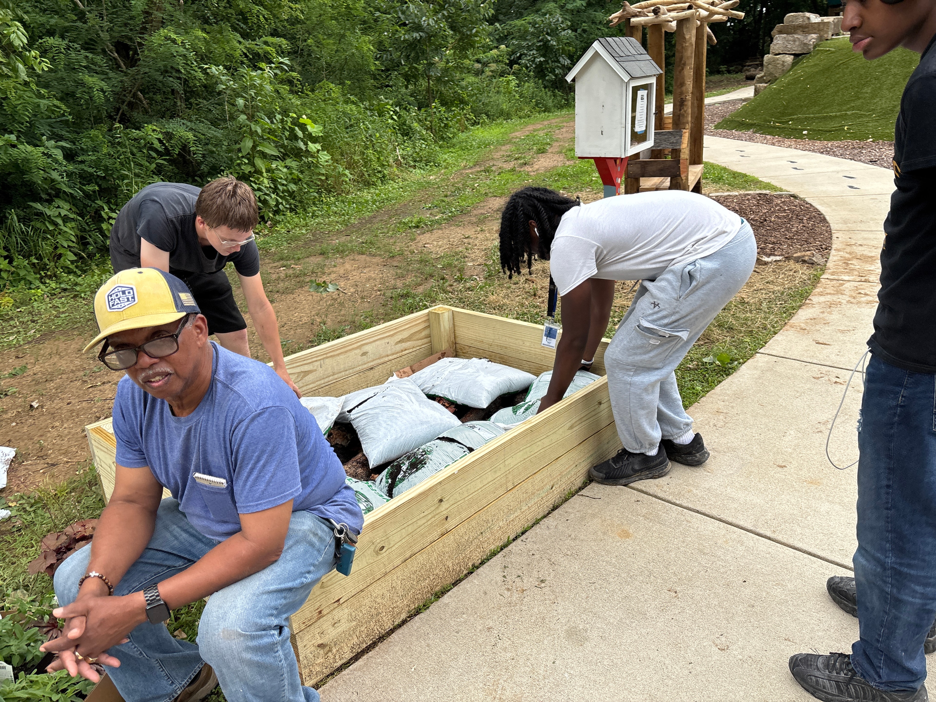 Youth and mentors building a raised garden bed outdoors at ACE Project summer enrichment