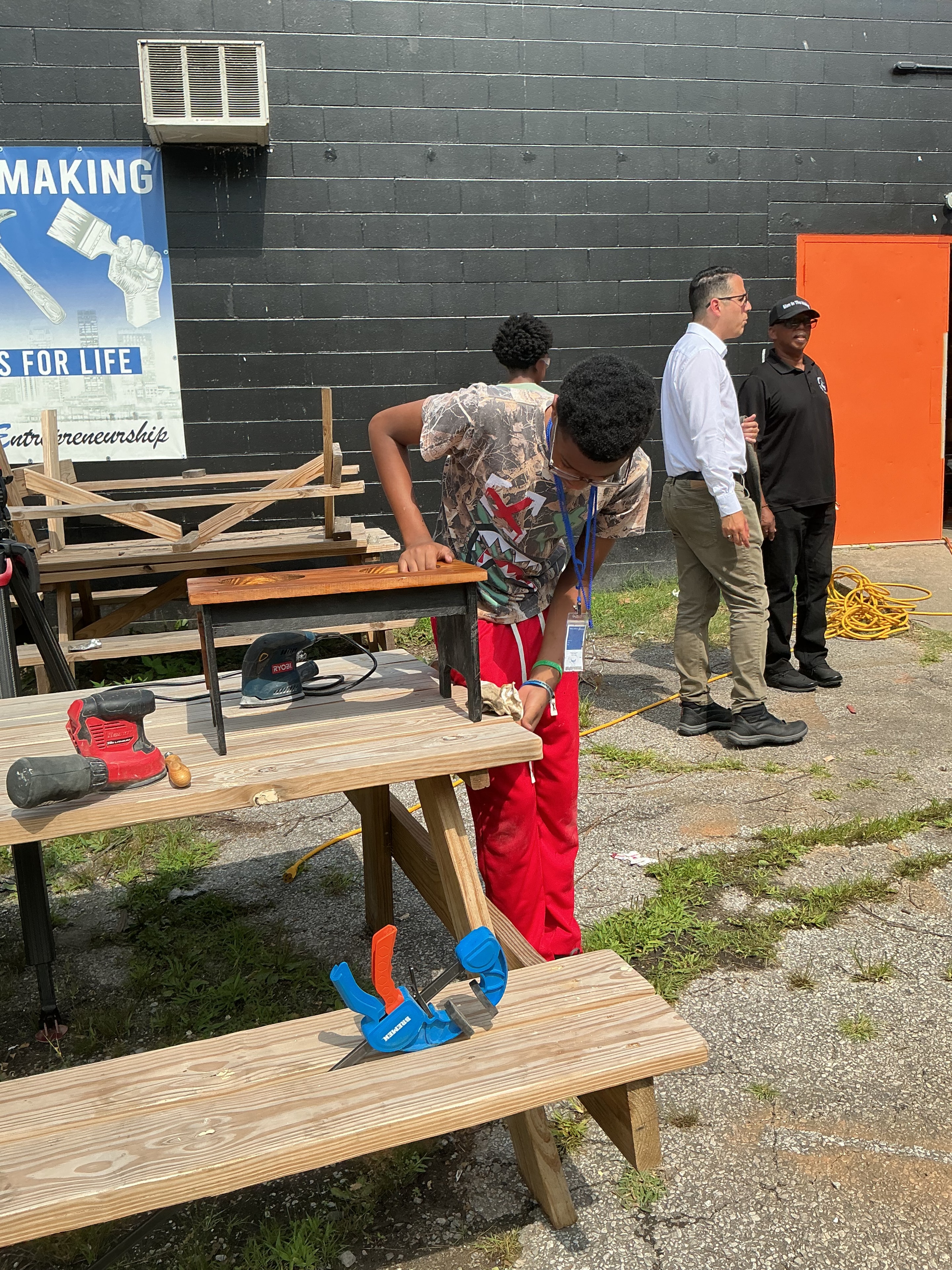 Youth and mentor working on a wooden bench outside the ACE Project Men in the Making woodshop